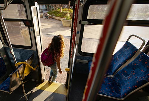 A young woman exits through the rear door of a boise bus